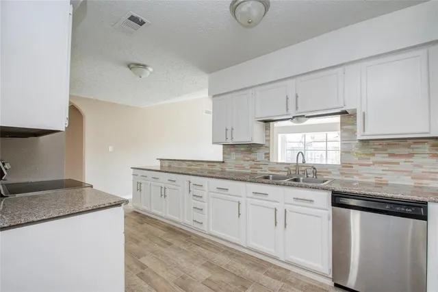 a kitchen with granite countertop white cabinets and a sink