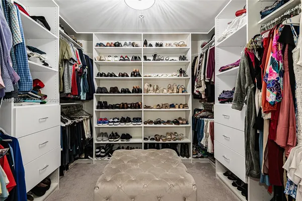 a view of walk in closet with clothes and shoes