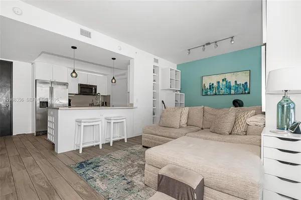 a living room with furniture white walls and kitchen view