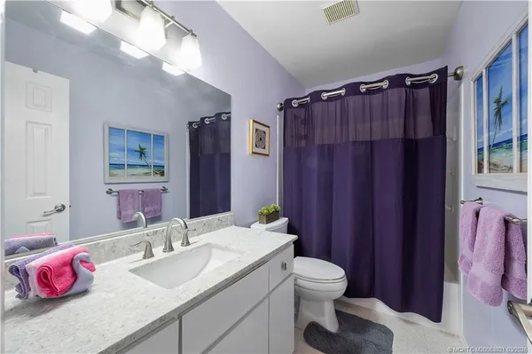 a bathroom with a granite countertop sink vanity mirror shower and toilet