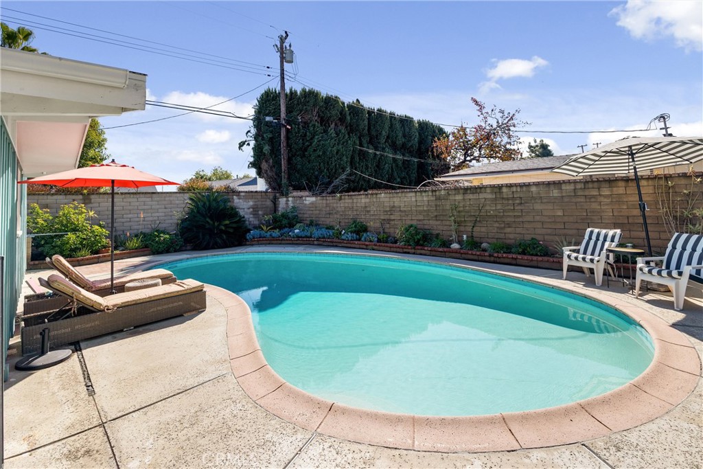 13062 Chaplet Place Tustin, CA 92780 - Photo 23 of 27 a view of a swimming pool with lawn chairs under an umbrella