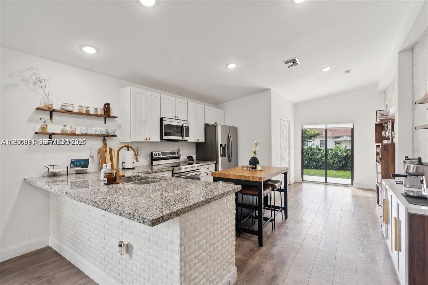 944 Northwest 64th Street Miami, FL 33150 - Photo 6 of 19 a kitchen with stainless steel appliances granite countertop sink stove top oven and cabinets