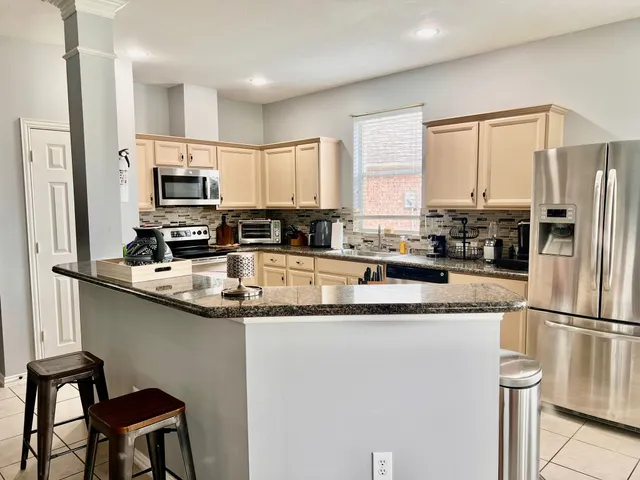 a kitchen with stainless steel appliances granite countertop a sink a stove a refrigerator a center island and a cabinets