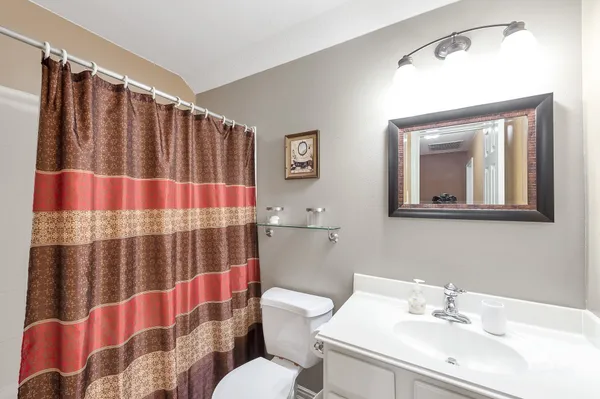 a bathroom with a sink a mirror a toilet and shower curtain