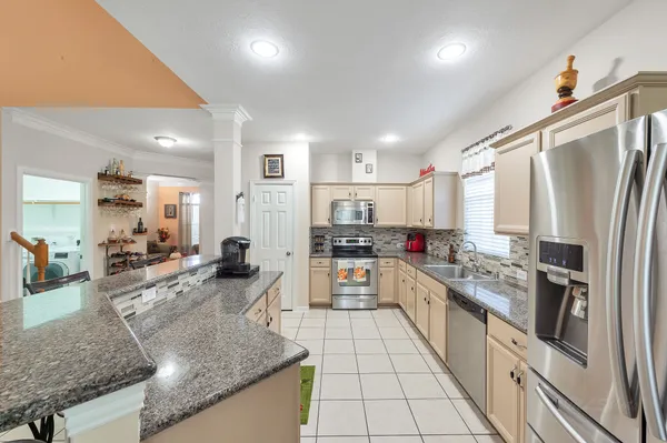 a large kitchen with stainless steel appliances kitchen island granite countertop a large counter top and white cabinets