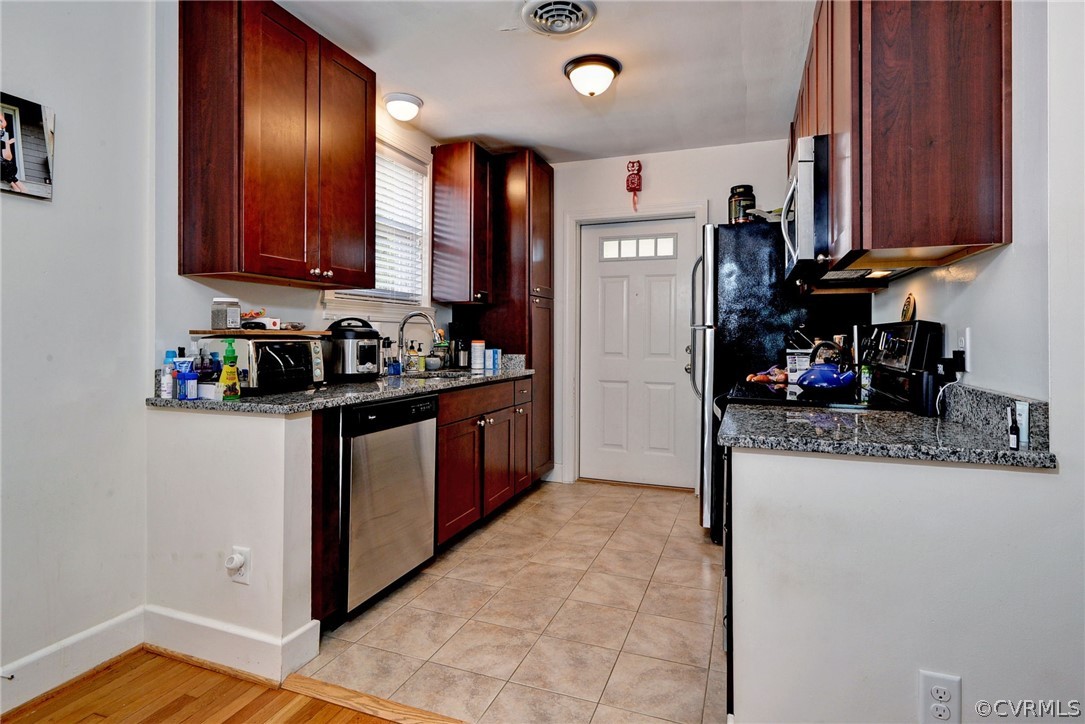 905 Lake Road Richmond, VA 23220 - Photo 34 of 50 a kitchen with stainless steel appliances granite countertop a refrigerator a stove top oven and a sink with wooden floor