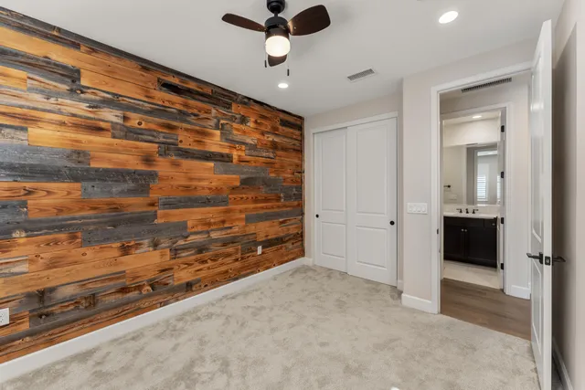 an empty room with a ceiling fan and carpet