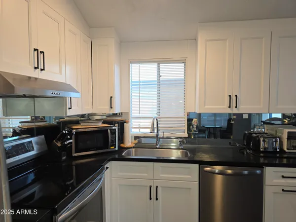 a kitchen with stainless steel appliances granite countertop a stove a sink and a microwave