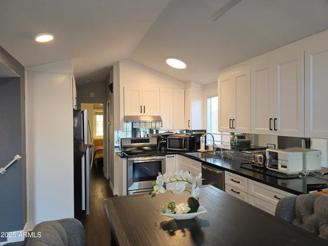 a kitchen with stainless steel appliances kitchen island granite countertop a sink dishwasher stove and refrigerator with wooden floor