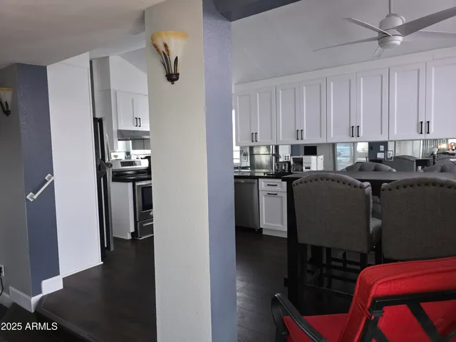 a view of kitchen with stainless steel appliances granite countertop dining table chairs cabinets and a refrigerator