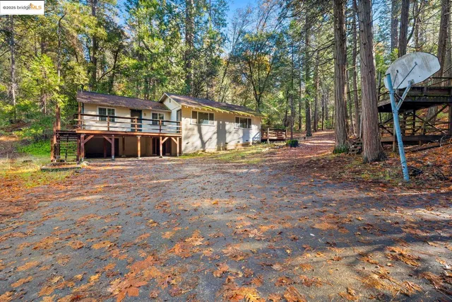 a view of a house with large tree and wooden fence