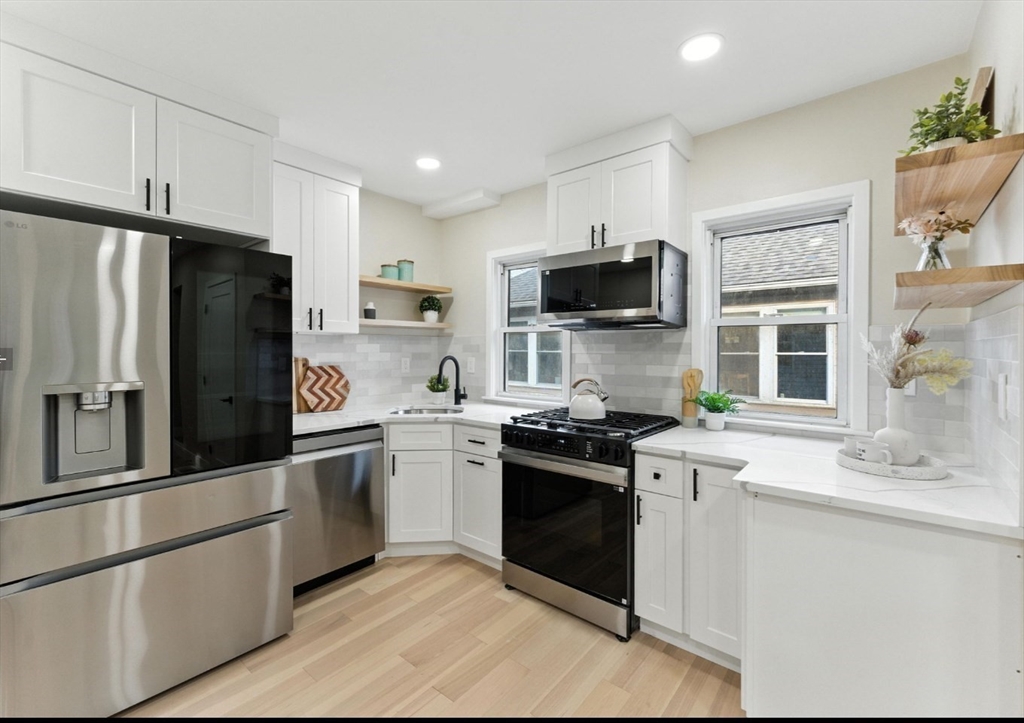 76 Orchard Street, Unit 76 Medford, MA 02155 - Photo 2 of 21 a kitchen with stainless steel appliances granite countertop a refrigerator stove microwave and sink