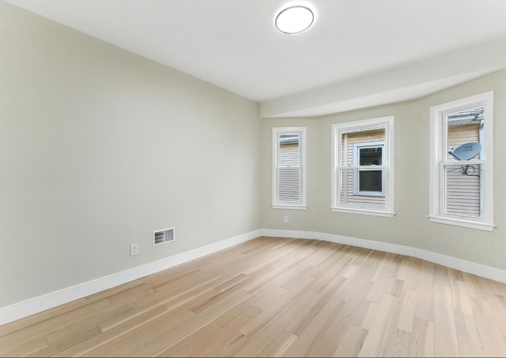 76 Orchard Street, Unit 76 Medford, MA 02155 - Photo 7 of 21 an empty room with wooden floor and windows