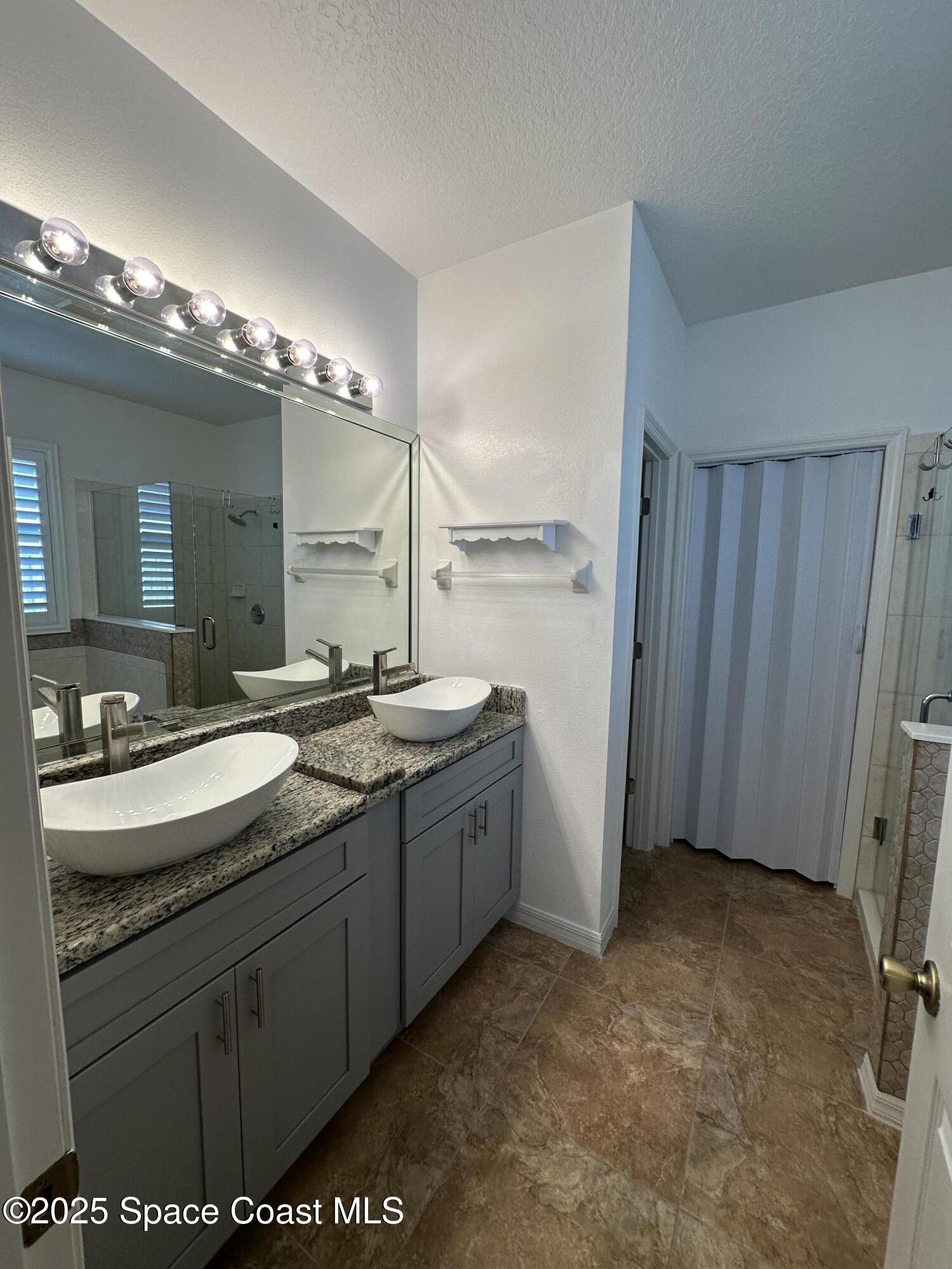 1354 Enclave Drive Rockledge, FL 32955 - Photo 12 of 27 a bathroom with a sink a mirror and a shower