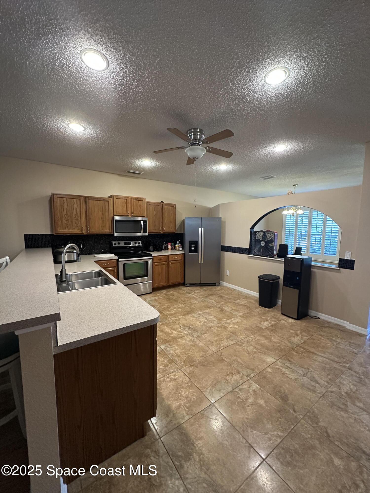 1354 Enclave Drive Rockledge, FL 32955 - Photo 3 of 27 a large kitchen with kitchen island a sink a counter and chairs