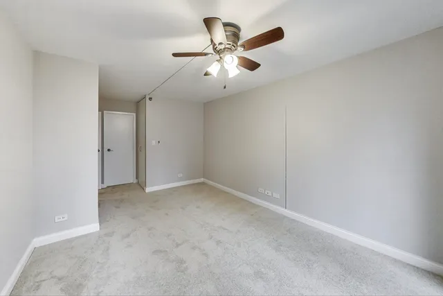 an empty room with ceiling fan and window