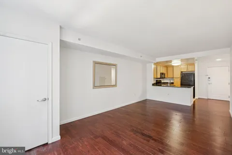 a view of a big room with wooden floor and a kitchen