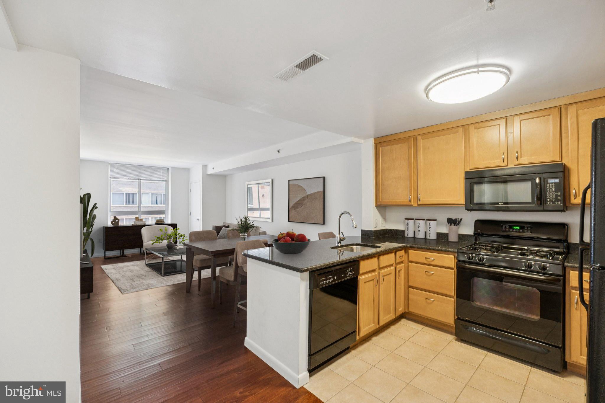 355 I Street Southwest, Unit 410 Washington, DC 20024 - Photo 3 of 31 a kitchen with stainless steel appliances granite countertop a stove top oven a sink dishwasher a dining table and chairs with wooden floor