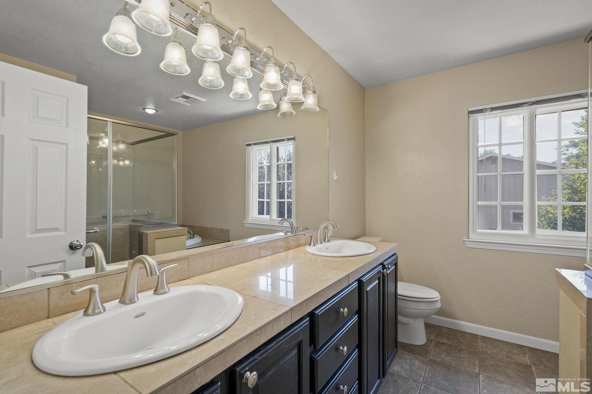 10055 Raintree Court Reno, NV 89511 - Photo 27 of 39 a bathroom with a granite countertop sink a toilet and a mirror