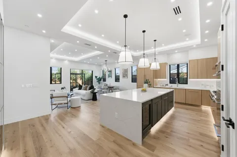 a large kitchen with a large counter top a sink stainless steel appliances and cabinets