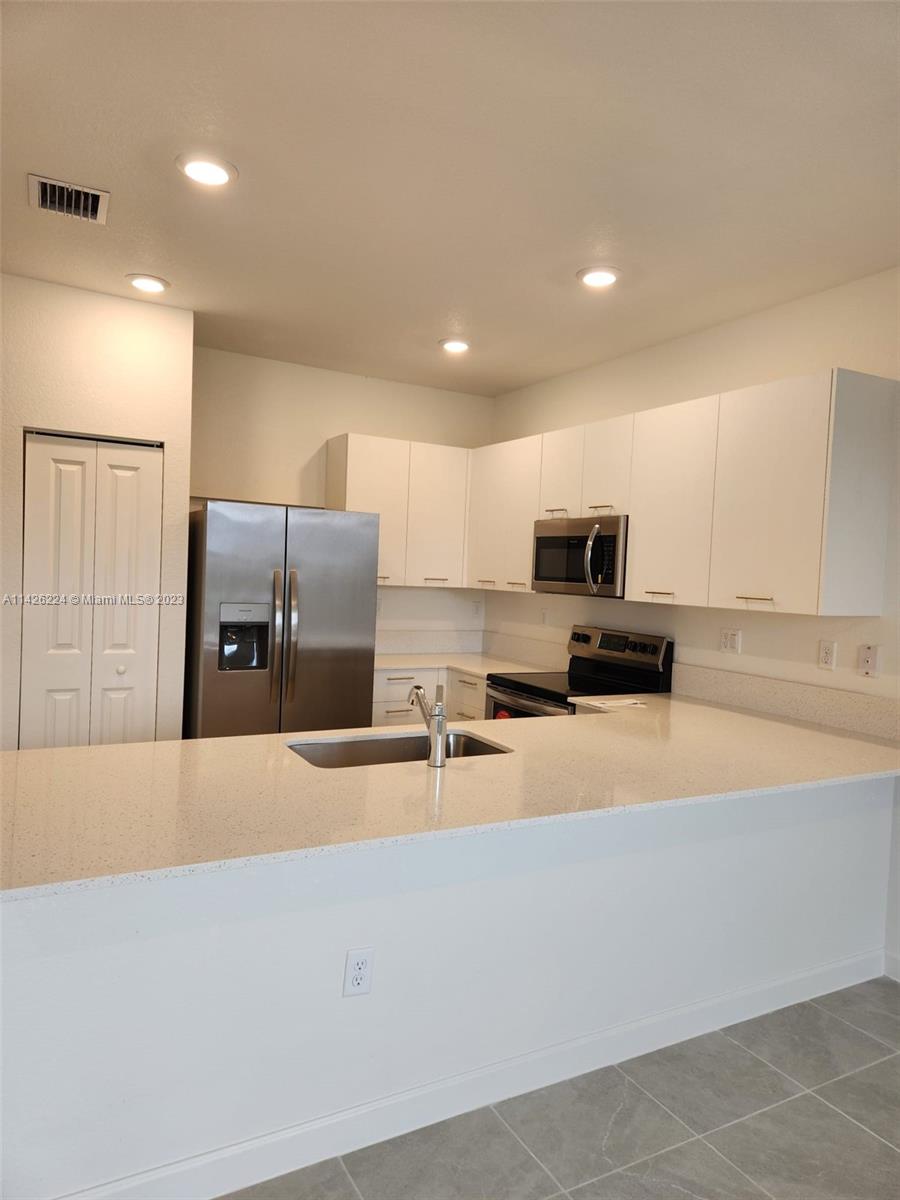 Miami-Dade County Miami, FL 33167 - Photo 9 of 18 a kitchen with stainless steel appliances a sink a stove a microwave a refrigerator and white cabinets