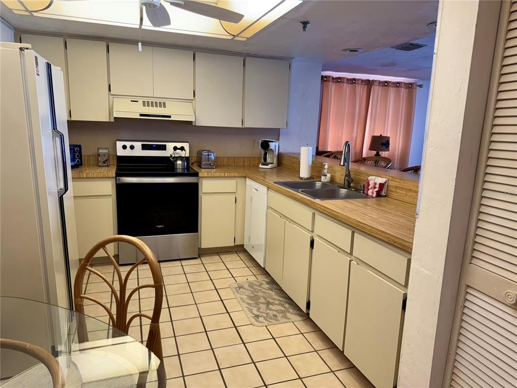 16330 Gulf Boulevard, Unit 201 Redington Beach, FL 33708 - Photo 11 of 30 a kitchen with stainless steel appliances a stove refrigerator sink and cabinets