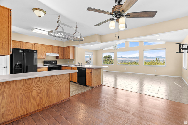 11934 South Cedar Ridge Road Sandy, UT 84094 - Photo 5 of 58 Kitchen featuring wood-finish cabinetry, black appliances, and an island with counter seating