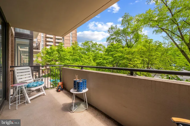 a balcony with table and chairs and potted plants