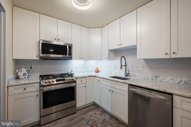 a kitchen with stainless steel appliances granite countertop a sink a stove a microwave and cabinets