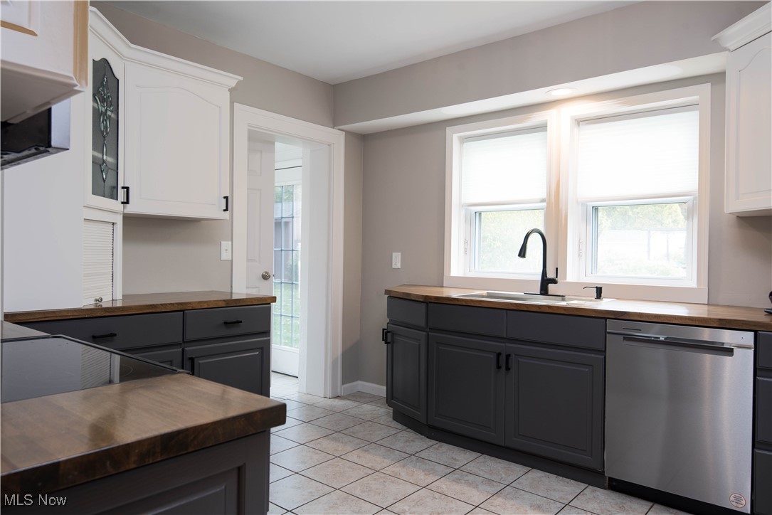 7003 Brecksville Road Independence, OH 44131 - Photo 27 of 35 Kitchen with dishwasher, gray cabinets, butcher block countertops, glass insert cabinets, and light tile patterned flooring
