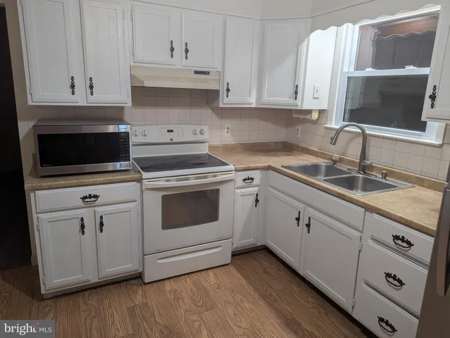 a kitchen with white cabinets and white appliances