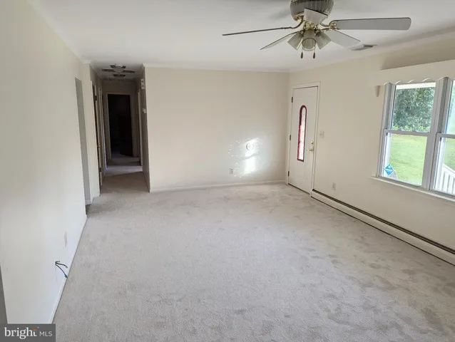 an empty room with windows and fan
