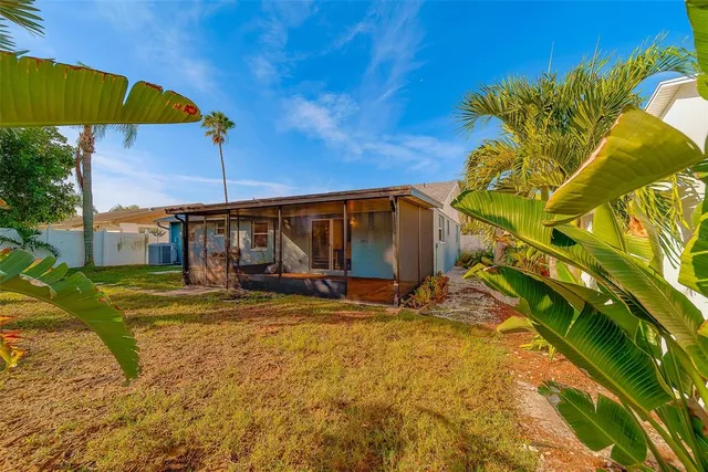 a backyard of a house with plants and palm tree
