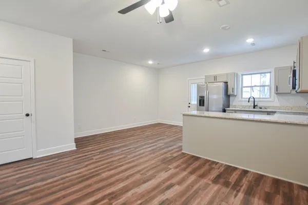 a view of kitchen and empty room with wooden floor
