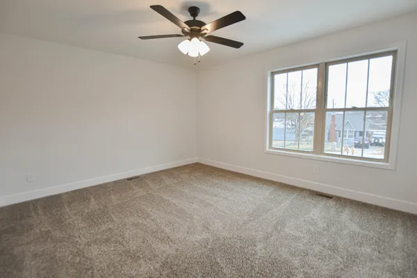 an empty room with a window and a fan