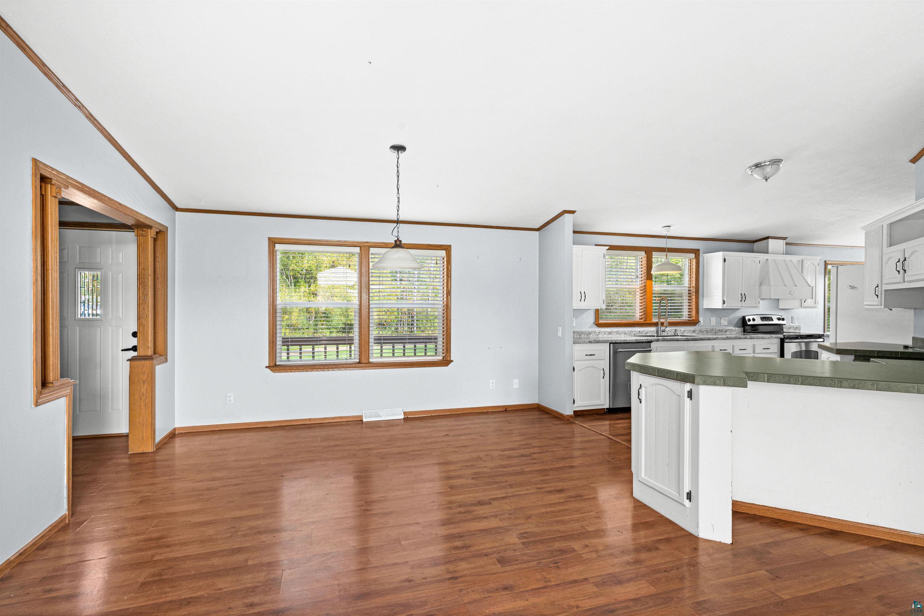 3126 Beyer Road Duluth, MN 55804 - Photo 10 of 23 Open-concept living space featuring laminate flooring, a kitchen with white cabinetry, stainless steel appliances, and a breakfast bar with a contrasting countertop