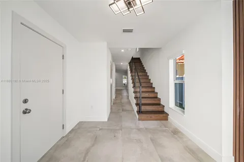 a view of a hallway with stairs and wooden floor