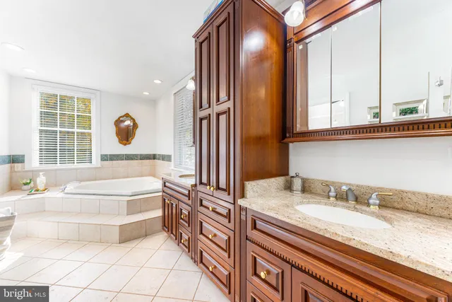 a bathroom with a granite countertop sink and a bathtub