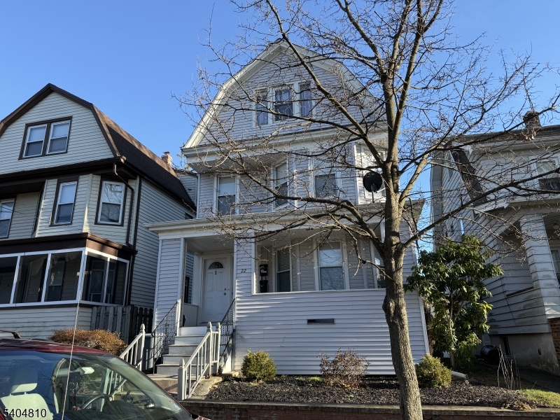 a front view of a house with large trees