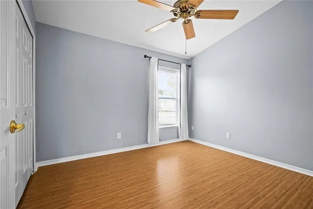 a view of an empty room with window and wooden floor