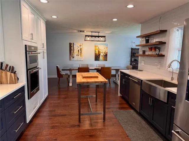 a kitchen with stainless steel appliances granite countertop a table chairs sink and cabinets