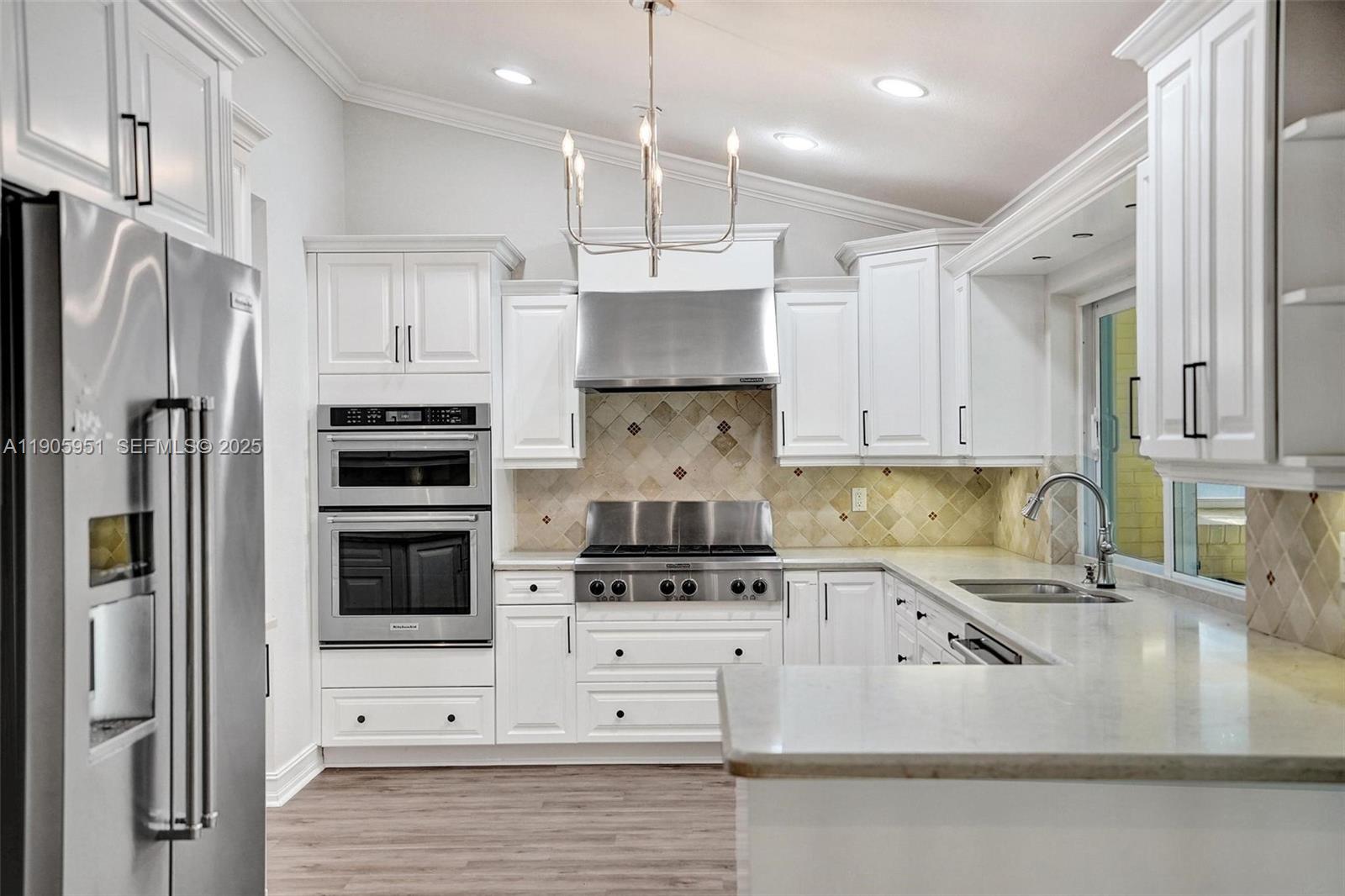 3801 Northwest 27th Avenue Boca Raton, FL 33434 - Photo 22 of 100 a kitchen with kitchen island granite countertop a refrigerator stove a sink and white cabinets with wooden floor
