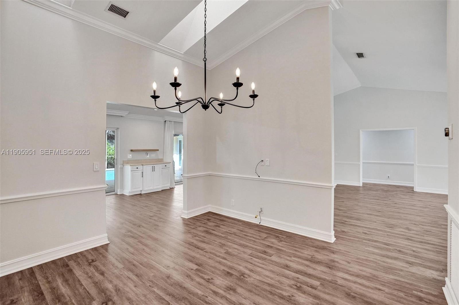 3801 Northwest 27th Avenue Boca Raton, FL 33434 - Photo 47 of 100 an empty room with wooden floor chandelier and windows