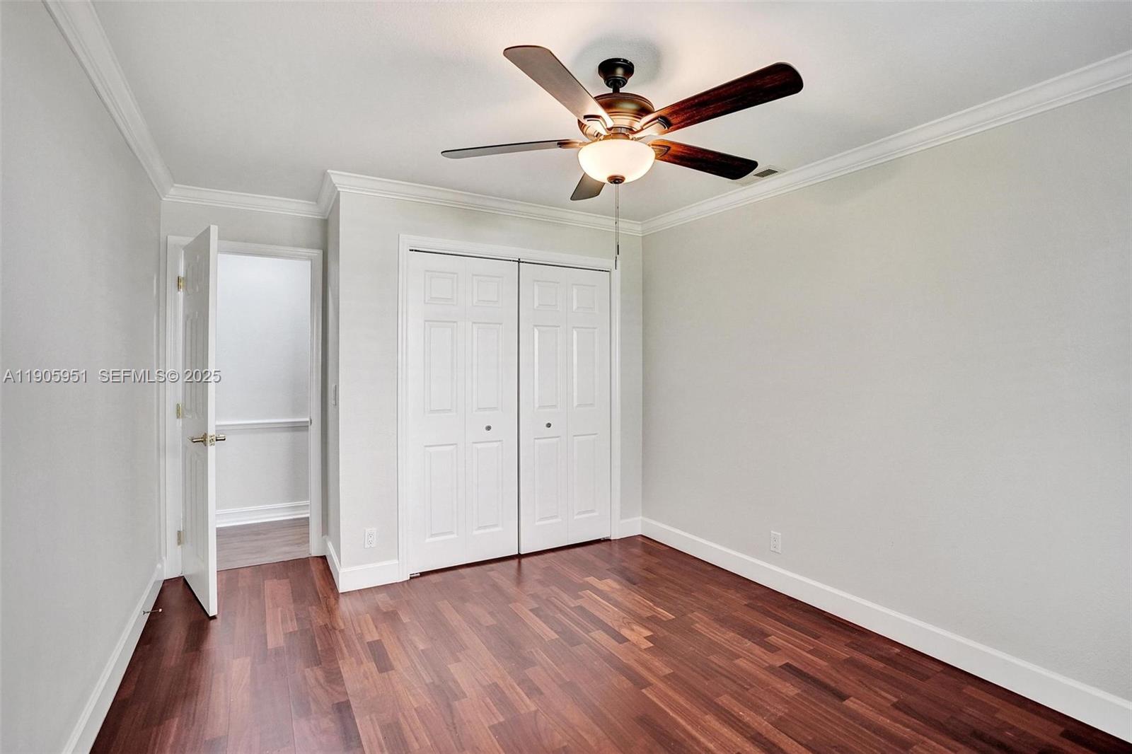3801 Northwest 27th Avenue Boca Raton, FL 33434 - Photo 70 of 100 an empty room with wooden floor and a ceiling fan
