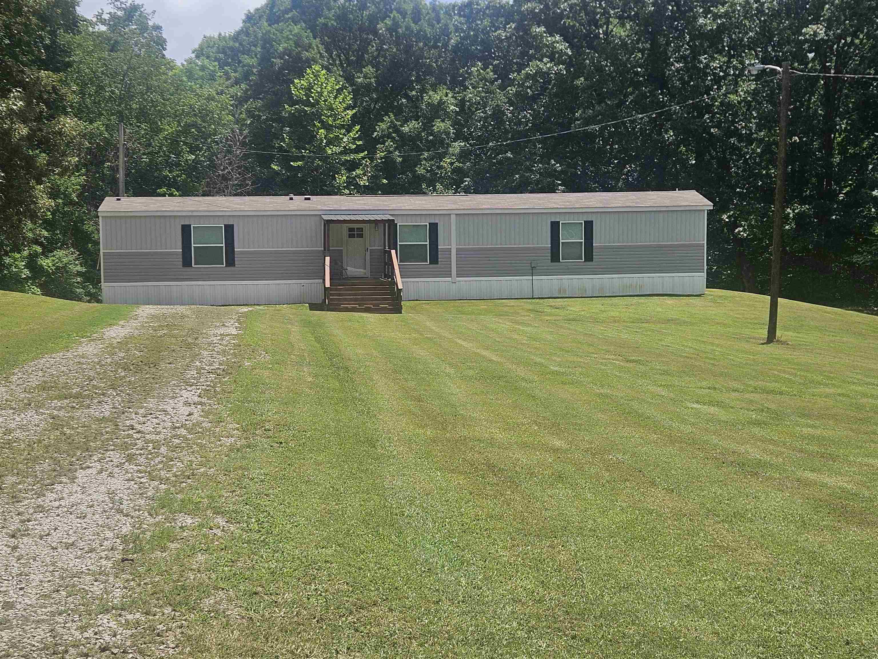 75 Pittman Road, Unit ROAD Somerville, TN 38068 - Photo 2 of 26 Manufactured home featuring two-tone siding, dark window shutters, a front entry with wooden steps, and an awning over the entry
