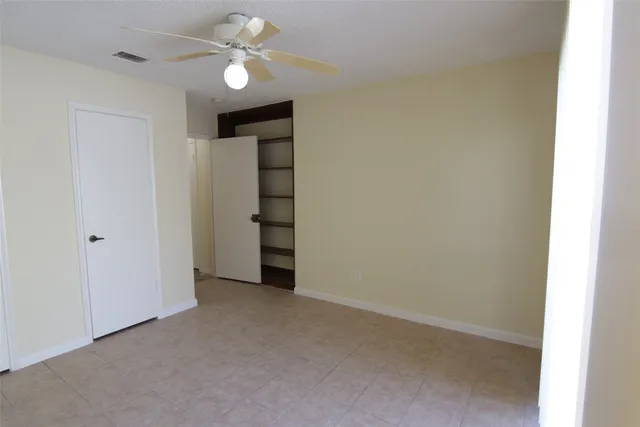 a view of an empty room with a ceiling fan and window