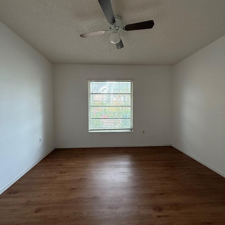 201 San Marco Avenue, Unit 1 North Port, FL 34287 - Photo 6 of 13 an empty room with wooden floor chandelier fan and windows