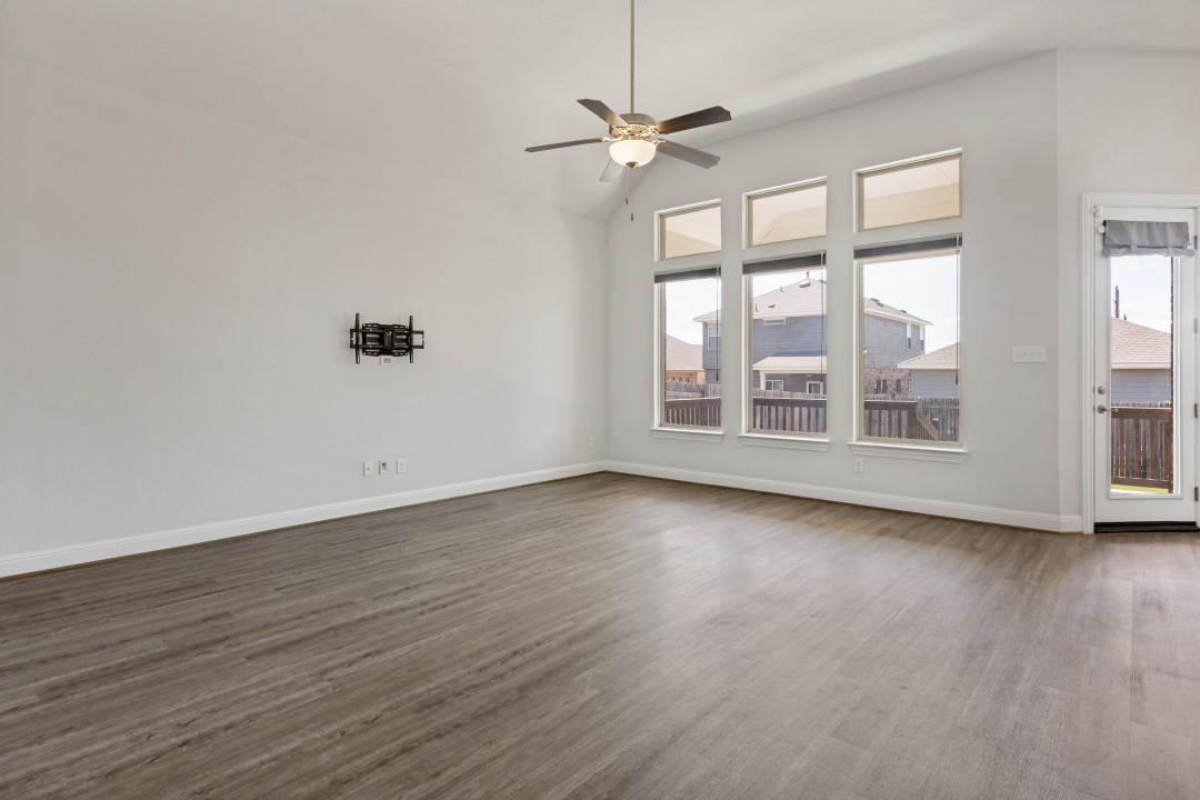 727 Spinnaker Loop Kyle, TX 78640 - Photo 5 of 29 Vaulted ceilings and handsome wood-inspired floors anchor this airy living space with tall windows.