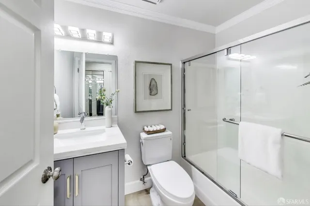 a bathroom with a toilet a sink a mirror a vanity and shower