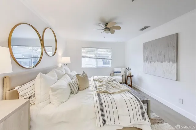 a bedroom with a bed a mirror and a large window